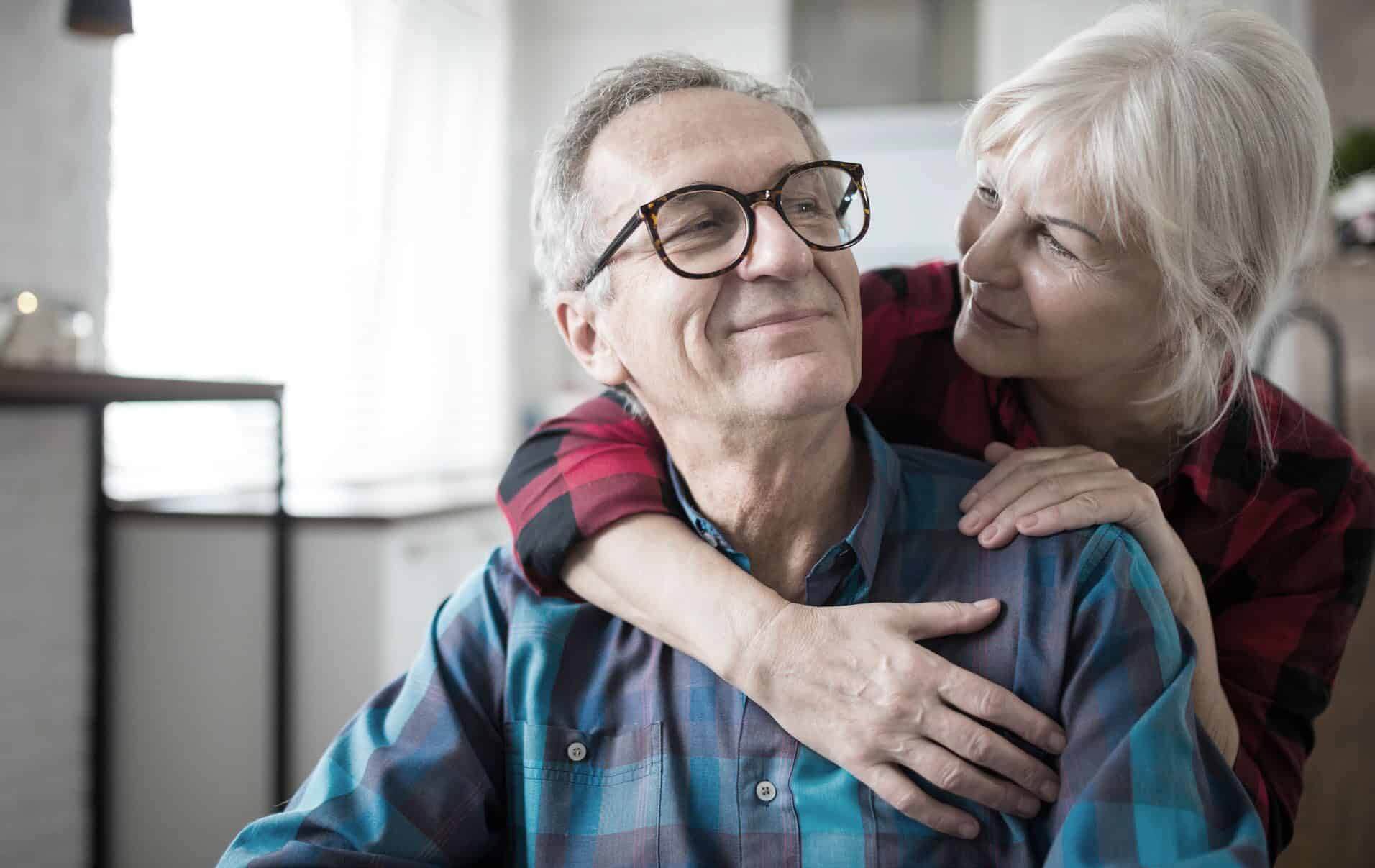Portrait of happy senior woman embracing her husband